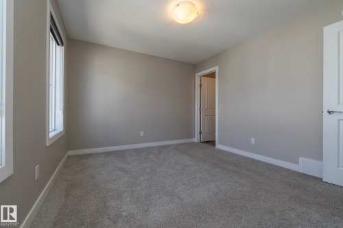 Neutral painted walls with white trim, gray carpet flooring, flush mount ceiling light fixture, and a paneled interior door with chrome hardware - 2610 Maple Way, Edmonton, AB 