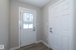 Entryway featuring light gray walls, white trim, and wood-finish flooring - 