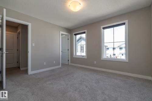 Carpeted room with neutral wall tones and two windows featuring white trim - 2610 Maple Way, Edmonton, AB 