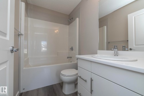 Bathroom featuring a white vanity with an integrated sink, chrome faucet, and expansive mirror - 2610 Maple Way, Edmonton, AB 