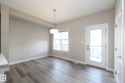 Open-concept living space featuring wood-finish flooring, a contemporary pendant light fixture, and a glass-paneled exterior door - 