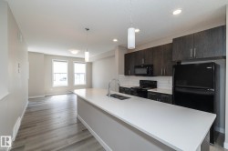 Kitchen featuring a central island with an undermount sink, dark wood-finish cabinetry, white subway tile backsplash, and black appliances - 
