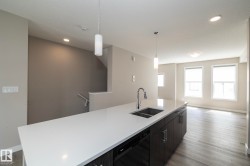 Kitchen island featuring a white countertop, stainless steel sink with a high-arch faucet, and dark wood-finish cabinetry - 