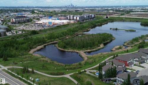 Aerial perspective showcasing a residential area with a prominent natural water feature, bordered by paved pathways and mature greenery - 2610 Maple Way, Edmonton, AB 