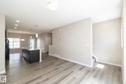 Spacious interior featuring wood-finish flooring and a central kitchen island with a light-toned countertop - 