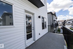 Private balcony featuring durable composite decking, black metal railings, and dual exterior wall sconces - 