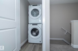 Stackable washer and dryer unit with a light wood-finish floor - 