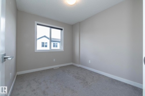 Neutral-toned wall finishes with gray carpeting, white trim, and a window with white casing - 2610 Maple Way, Edmonton, AB 