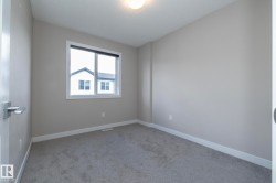 Neutral-toned wall finishes with gray carpeting, white trim, and a window with white casing - 