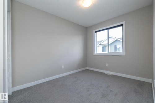 Neutral-toned room featuring grey carpet, white baseboards, and a single window with white trim - 2610 Maple Way, Edmonton, AB 