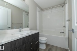 Bathroom featuring a wood-finish vanity with an integrated white sink, a solid surface countertop, and chrome fixtures - 