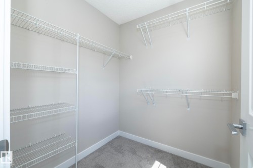 Walk-in closet featuring light gray wall paint, white wire shelving, white baseboards, and gray carpet flooring - 2610 Maple Way, Edmonton, AB 
