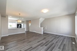 Spacious living area featuring wood-finish flooring, neutral wall tones, and recessed lighting - 
