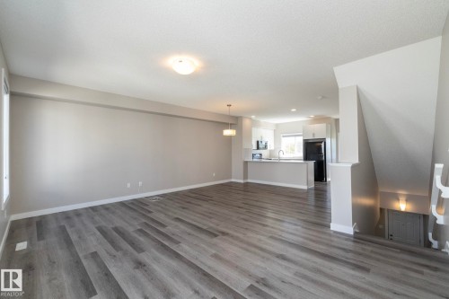 Open-concept living space featuring wood-finish flooring, neutral wall tones, and recessed lighting - 2610 Maple Way, Edmonton, AB 