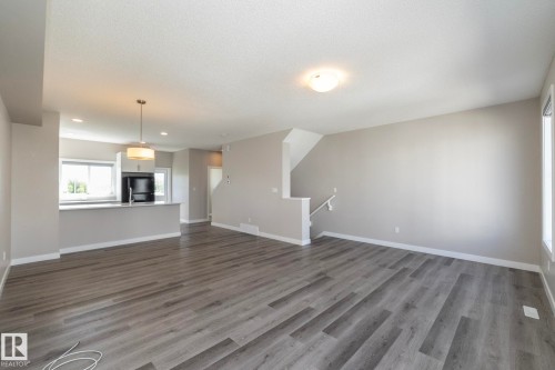 Spacious living area featuring wood-finish flooring, neutral wall tones, and recessed lighting - 2610 Maple Way, Edmonton, AB 