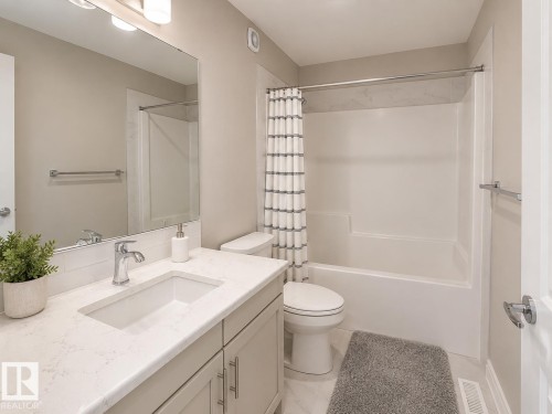 Bathroom featuring a single vanity with an integrated sink, polished chrome faucet, and light-toned countertop - 7274 Morgan Road, Edmonton, AB 