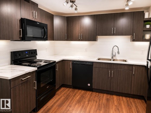 Contemporary kitchen featuring wood-grain cabinetry with brushed nickel hardware, white stone-finish countertops, and a subway tile backsplash - 7274 Morgan Road, Edmonton, AB 