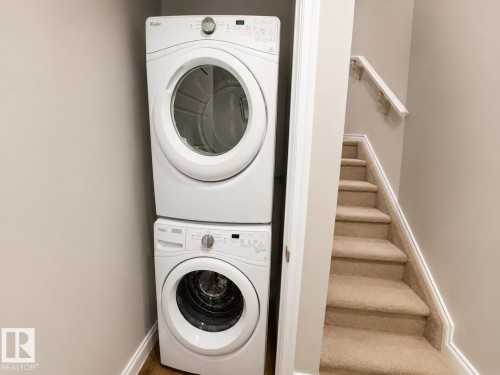 White stackable washer and dryer unit, complemented by neutral wall tones - 7274 Morgan Road, Edmonton, AB 