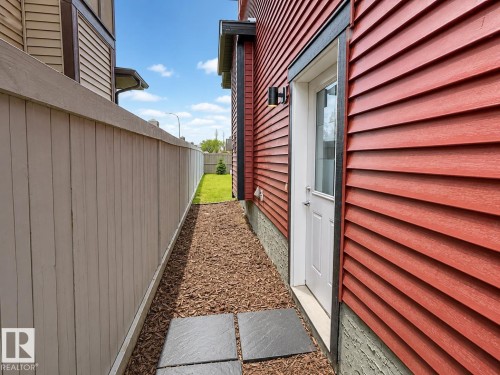 Red siding exterior with a white door featuring a window insert - 7274 Morgan Road, Edmonton, AB 