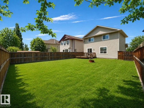 Expansive backyard featuring a lush lawn, privacy fencing, and a wooden deck - 7407 Singer Landing, Edmonton, AB 