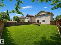 Expansive backyard featuring a lush lawn, privacy fencing, and a wooden deck - 