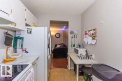 Compact kitchen featuring white cabinetry, a refrigerator, a smooth-top range, and light-colored countertops - 