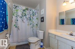Full bathroom featuring a white vanity with integrated sink, two wall-mounted mirrored medicine cabinets, an overhead light fixture, and a toilet - 