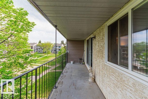 Exterior balcony featuring textured stucco siding and a sliding glass door - 6 3819 76 Street, Edmonton, AB 