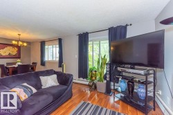 Living space featuring wood-finish flooring and a dining area with an overhead chandelier - 