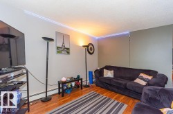 Living area featuring wood-finish flooring, light-toned walls, and a contrasting accent wall - 