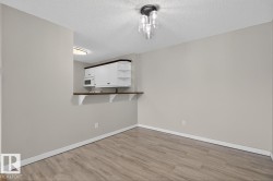Open concept living area featuring wood-finish flooring and a contemporary overhead light fixture - 