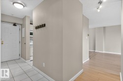 Entryway featuring neutral wall paint, white baseboards, and a combination of light-toned tile and wood-finish flooring - 