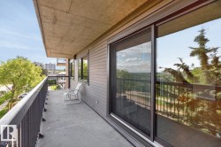 Expansive concrete balcony featuring a dark metal railing, gray horizontal siding, and large sliding glass doors with an integrated screen - 