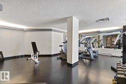 Dedicated fitness area featuring durable black flooring, expansive mirrored wall, and overhead lighting - 