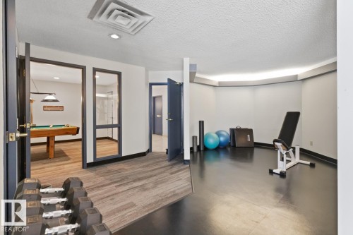 Versatile recreation area featuring a dedicated fitness zone with dark flooring, light cove ceiling, and perimeter accent lighting - #405 10545 Saskatchewan Dr Nw, Edmonton, AB - Indoor