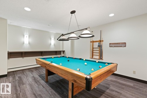 Recreation room featuring a pool table with an overhead light fixture, wood-finish flooring, recessed lighting, wall sconces, and a built-in wall shelf - #405 10545 Saskatchewan Dr Nw, Edmonton, AB - Indoor Photo Showing Other Room