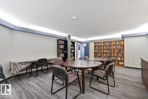 Community room featuring extensive built-in shelving, wood-finish flooring, and recessed ceiling lighting - #405 10545 Saskatchewan Dr Nw, Edmonton, AB - Indoor
