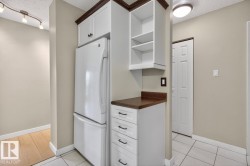 White refrigerator unit integrated with custom cabinetry featuring a dark wood trim and open shelving - 
