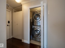 Integrated laundry closet featuring stacked stainless steel front-load appliances and bifold doors - 