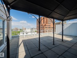 Expansive rooftop terrace featuring a metal gazebo, string lighting, and concrete paver flooring - 