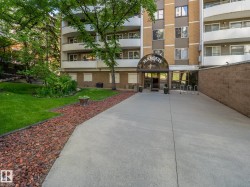 Building exterior featuring a glass-enclosed entrance with a prominent "MARQUIS" sign, surrounding concrete pathways, and a brick accent wall - 