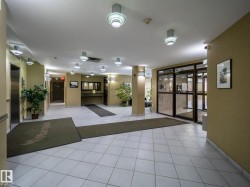 Lobby featuring white square tile flooring, recessed and wall-mounted lighting, and an elevator bank with a stainless steel door - 