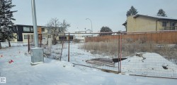 Fenced lot featuring a partially cleared area and surrounding residential structures - 
