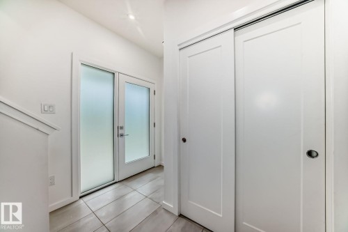 Entryway featuring frosted glass double doors, white trim, recessed lighting, and tile flooring - #67 5 Rondeau Dr, St. Albert, AB - Indoor Photo Showing Other Room