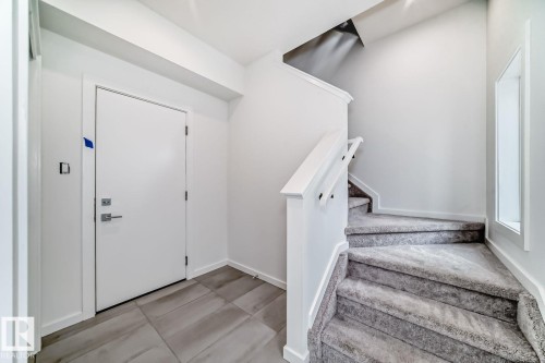 Entryway featuring a staircase with carpeted treads and a painted railing - #67 5 Rondeau Dr, St. Albert, AB - Indoor Photo Showing Other Room