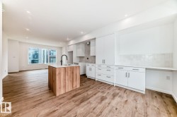 Open-concept living area featuring wood-finish flooring, recessed lighting, and a kitchen island with a built-in sink and matte black faucet - 