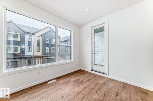 Bright interior space featuring a large picture window, a separate glass-paneled door, recessed ceiling lighting, wood-finish flooring, and crisp white baseboards - #67 5 Rondeau Dr, St. Albert, AB - Indoor Photo Showing Other Room