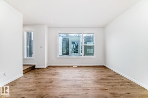Spacious room featuring wood-finish flooring, white baseboards, and clean white walls - #67 5 Rondeau Dr, St. Albert, AB - Indoor Photo Showing Other Room