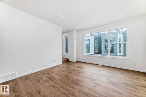 Spacious living area featuring wide-plank wood-finish flooring, a large picture window, and recessed lighting - #67 5 Rondeau Dr, St. Albert, AB - Indoor Photo Showing Other Room