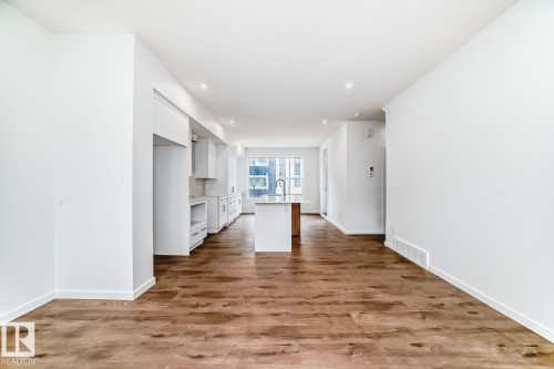 Expansive open-concept living area featuring wood-finish flooring, recessed lighting, and a kitchen island with an undermount sink and a gooseneck faucet - #67 5 Rondeau Dr, St. Albert, AB - Indoor